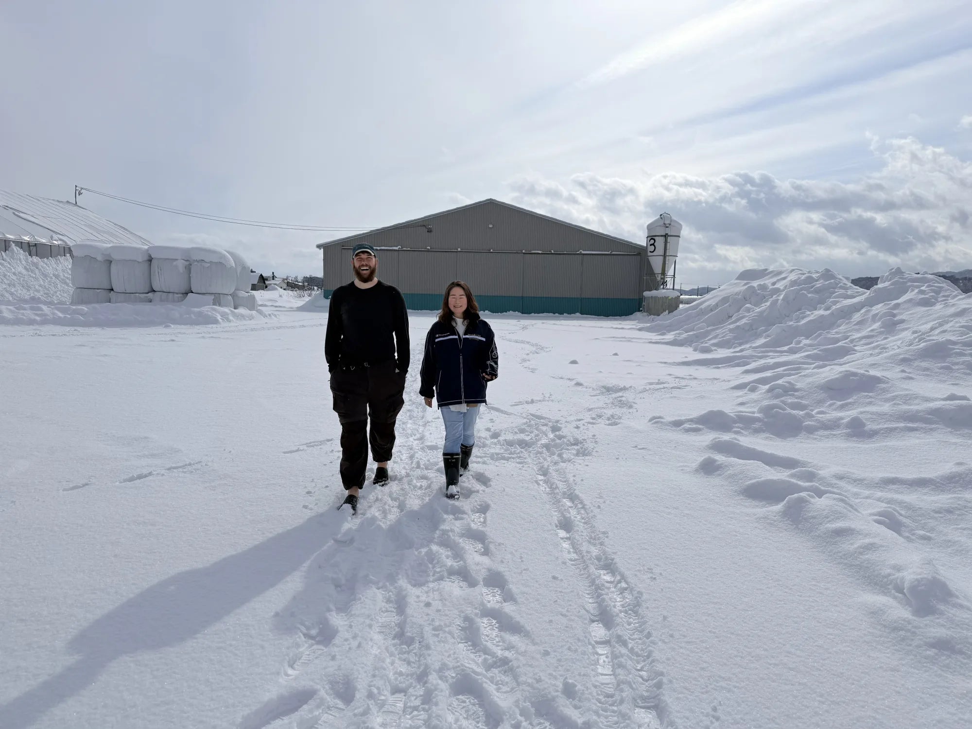 Matt and Ellie Takeda walking together across the snowy farm