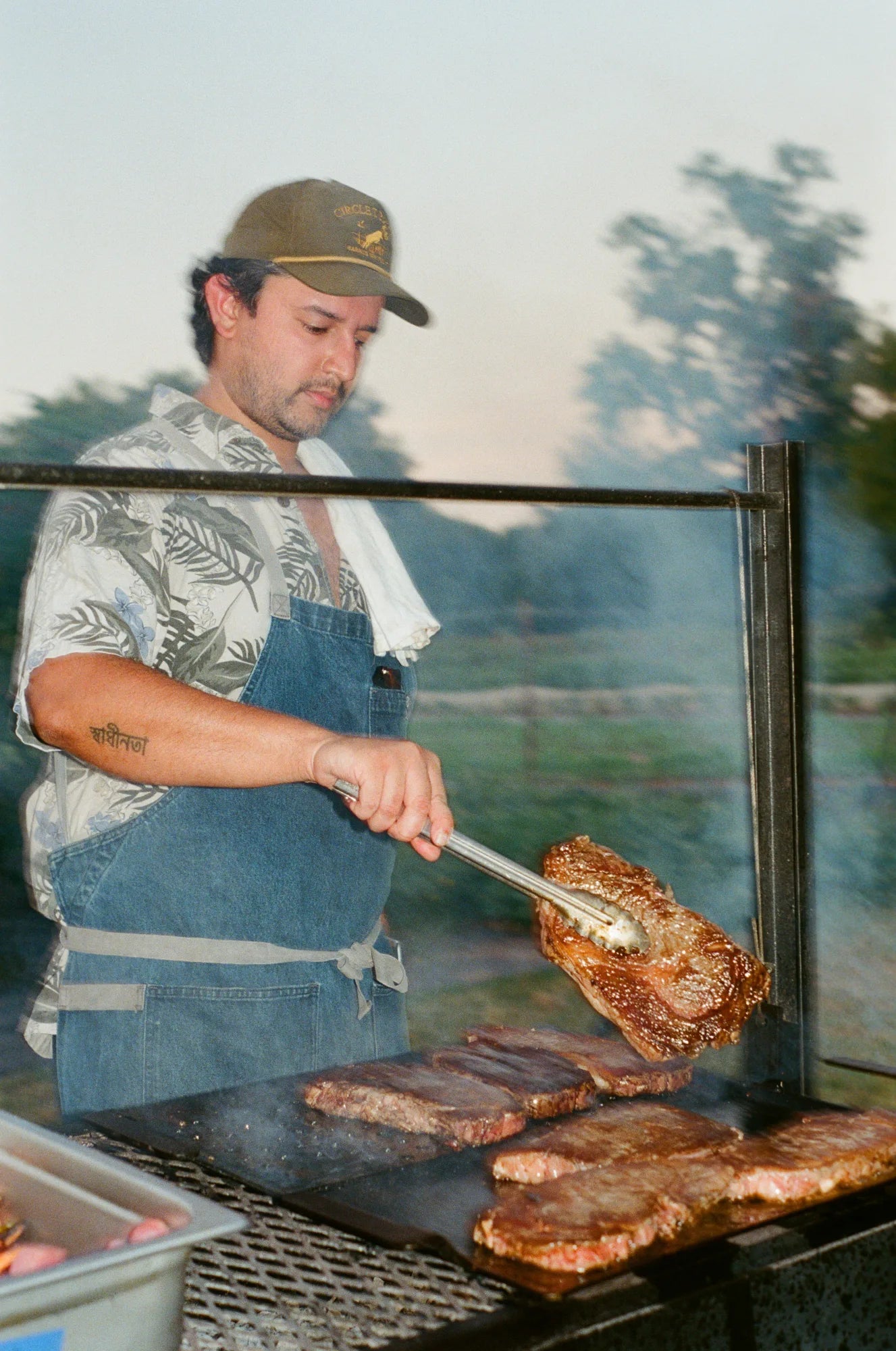 Chef flipping a NY strip through the smoke