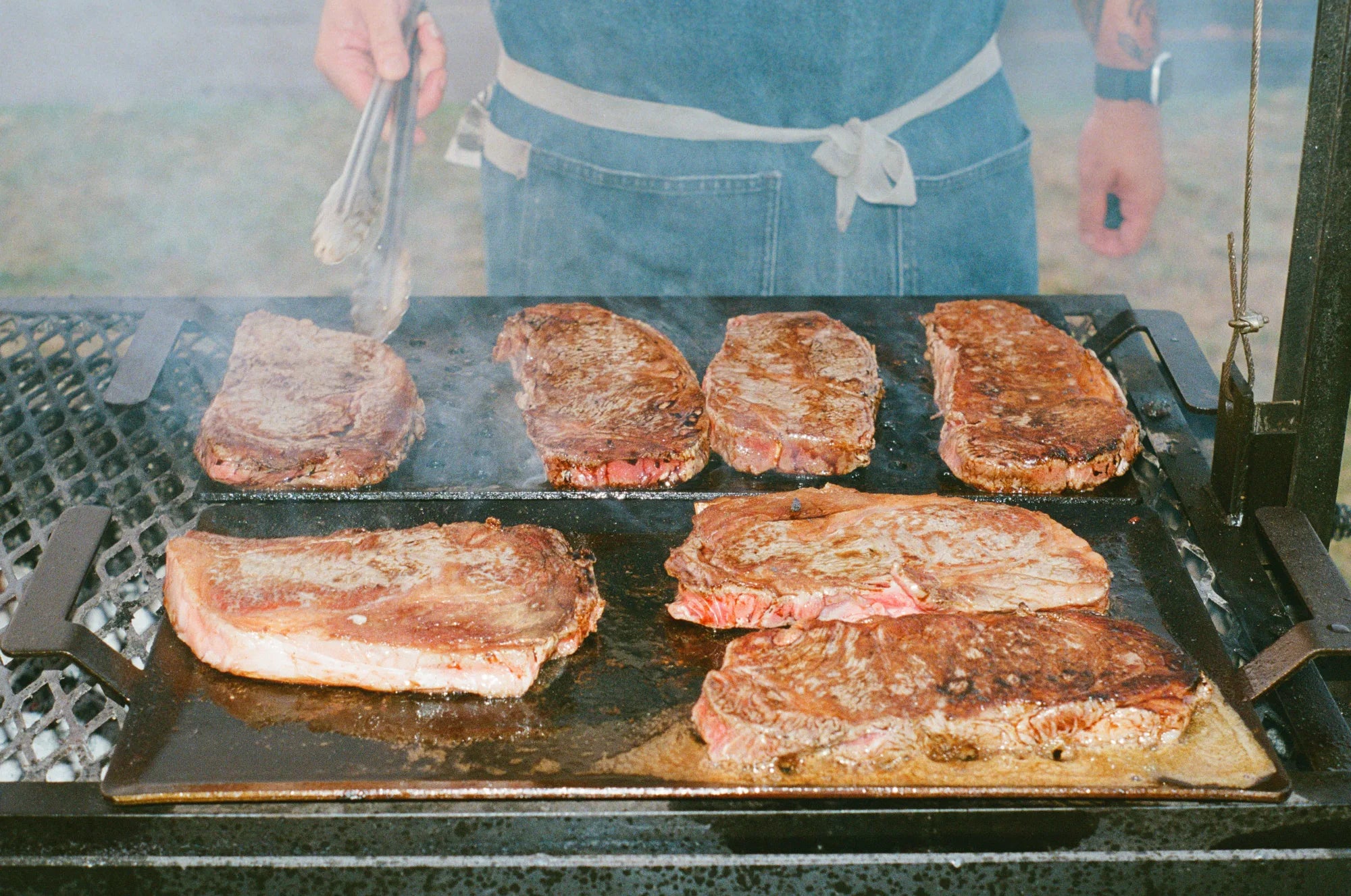 NY strips searing on the grill